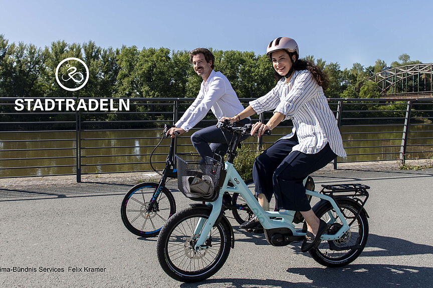 StadtRadeln 2026 Man und fRau auf Rädern fahren am Fluss entlang